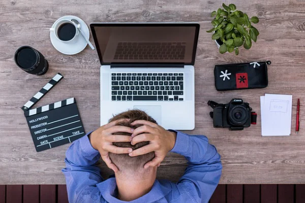 Person holding head at desk with laptop